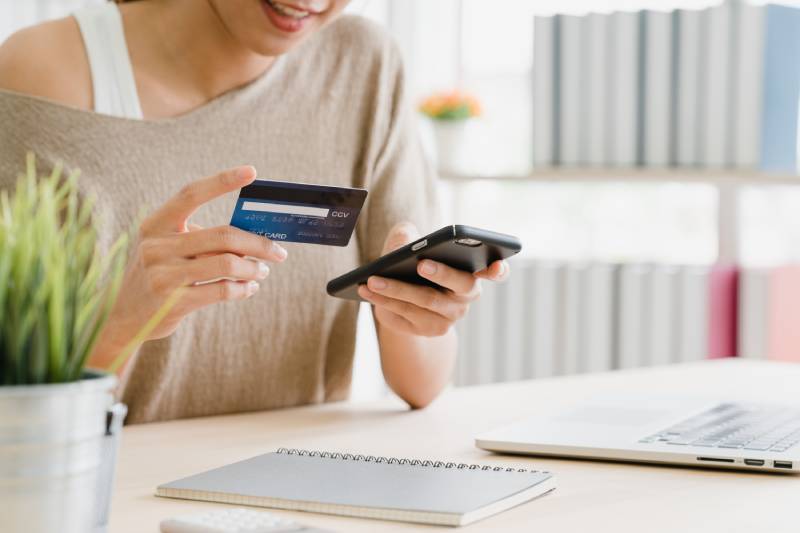 Imagem mostra mulher pagando com cartão de crédito uma compra feita pelo celular.