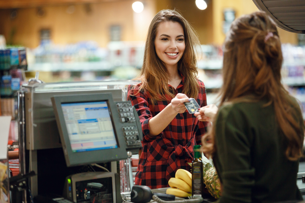 Mulher pagando compras no supermercado com cartão de crédito