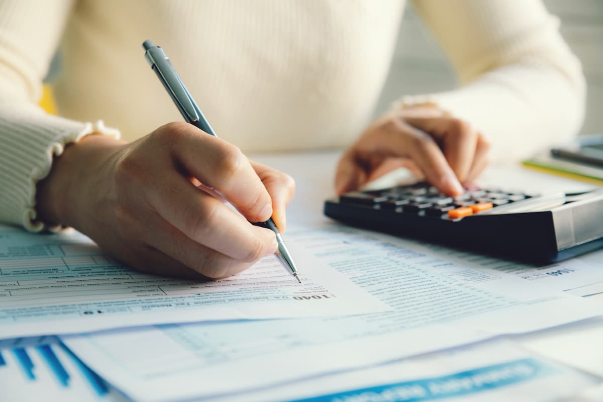 Uma pessoa calculando seu imposto de renda, e anotando as informações no papel
