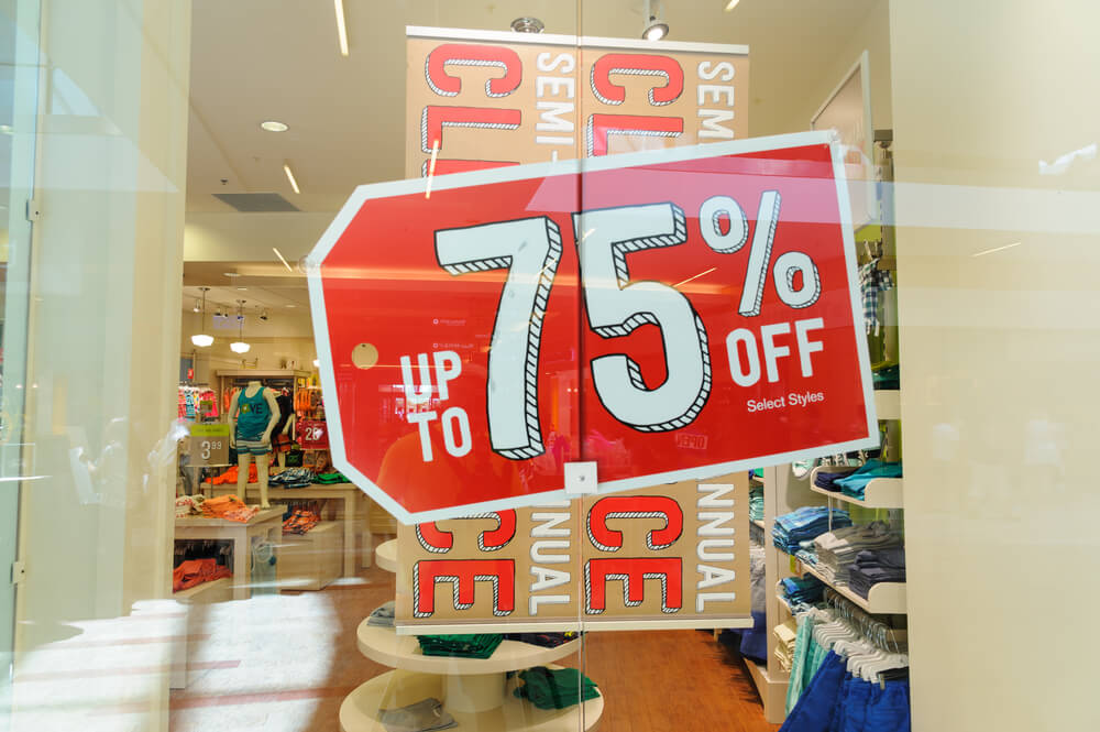 Vitrine exibindo uma grande placa de venda "75% de desconto", indicando uma grande promoção de vendas 

